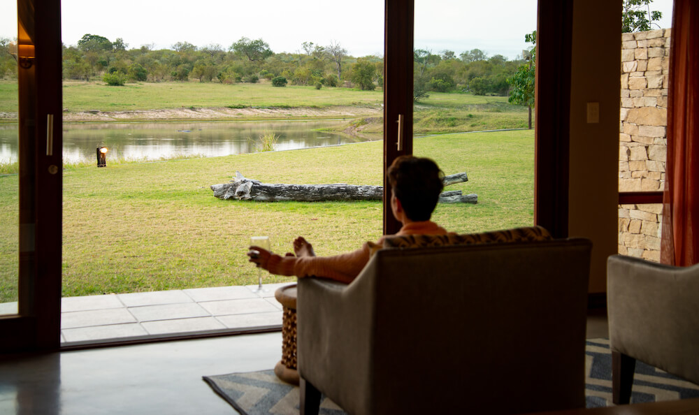 person-sitting-on-a-couch-holind-a-glass-of-wine-looking-out-the-door-at-a-waterhole